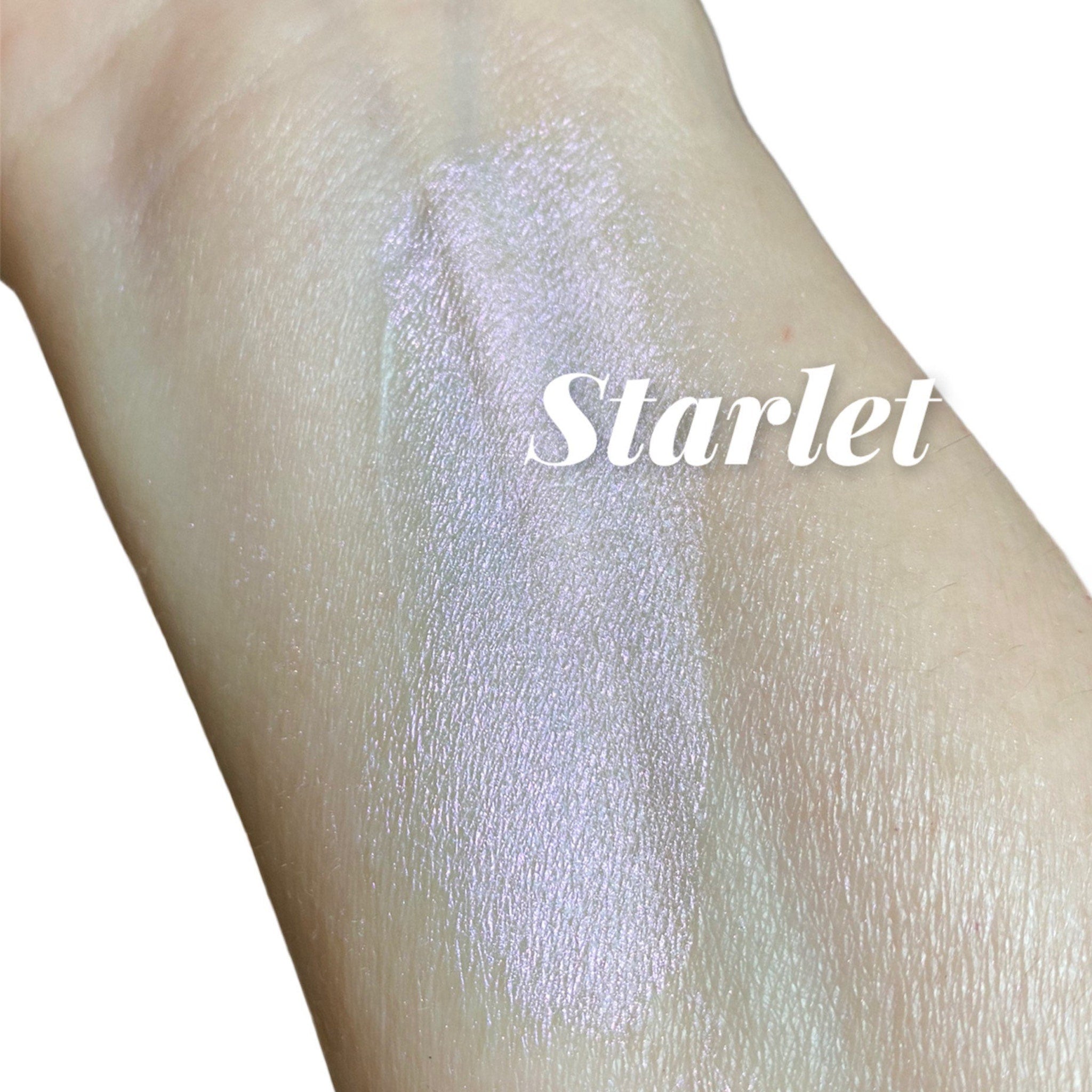 Swatched highlighter with iridescent shimmer on skin, "Starlet" text overlayed