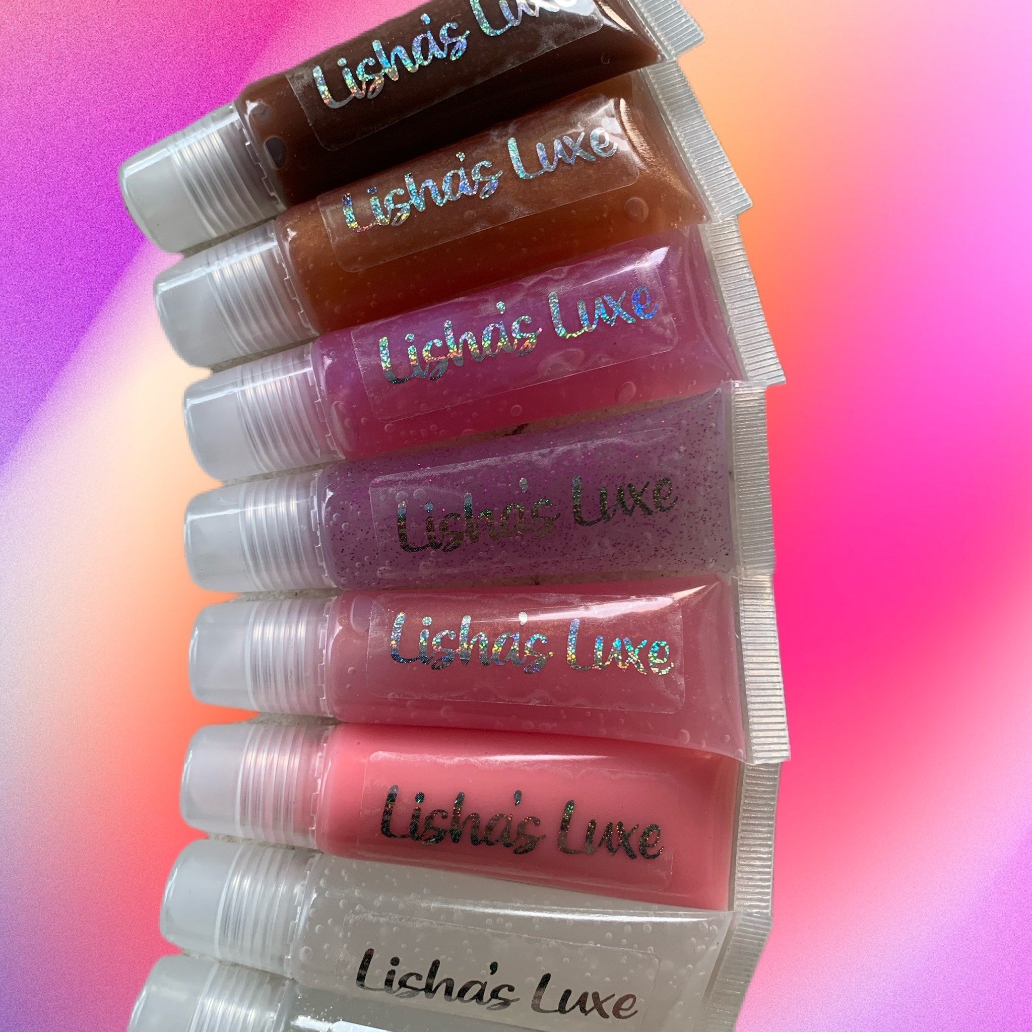Lip gloss tubes in assorted colors, clear plastic tubes with white caps, Lishas Luxe label visible