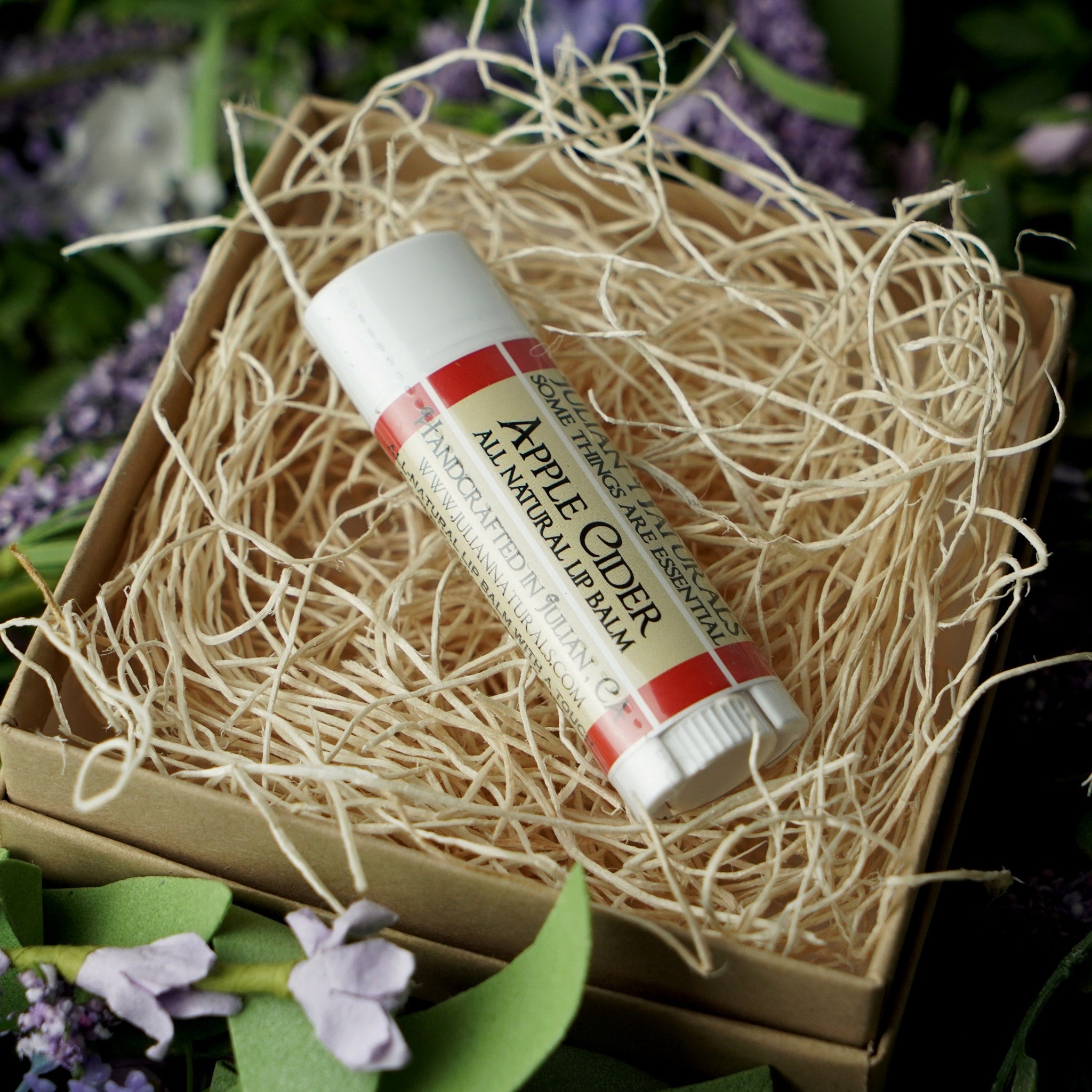 Lip balm tube with red and white label, in a gift box with straw filler, Julian Naturals brand
