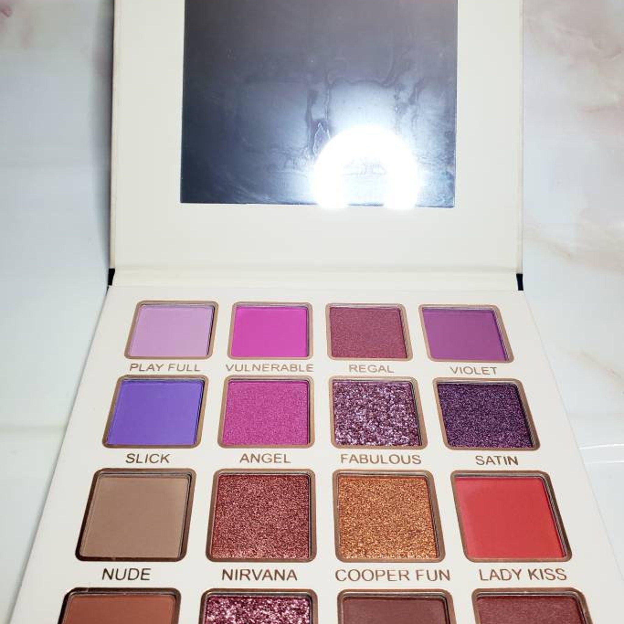 Eye makeup palette with various colors, including purple, pink, and brown shades, with Bella Forever brand name visible