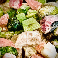 Colorful gemstone crystals in pink, green, and beige hues with rough textures and varying shapes