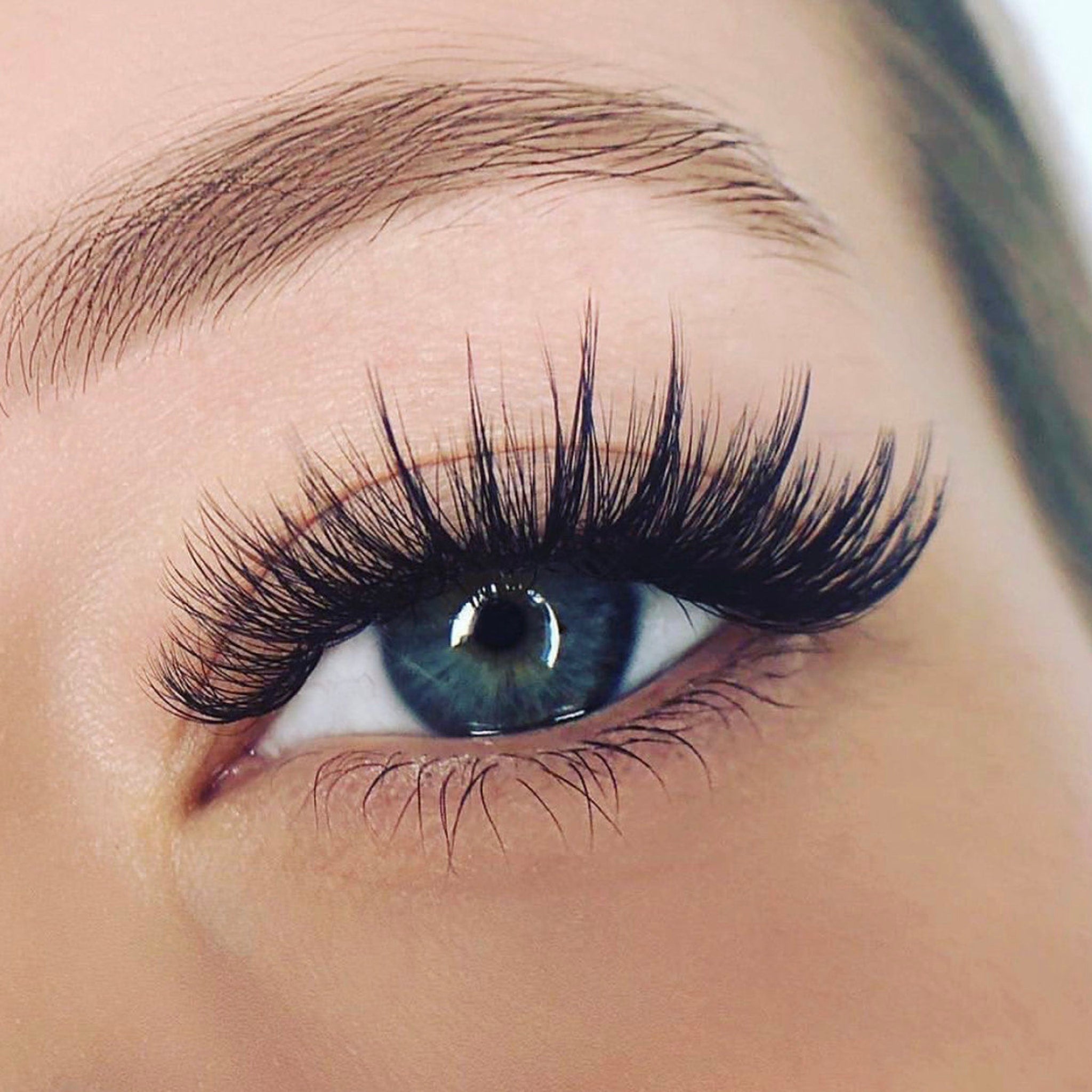 Eyelashes with dark black color, long and curved style, and blue eye color visible