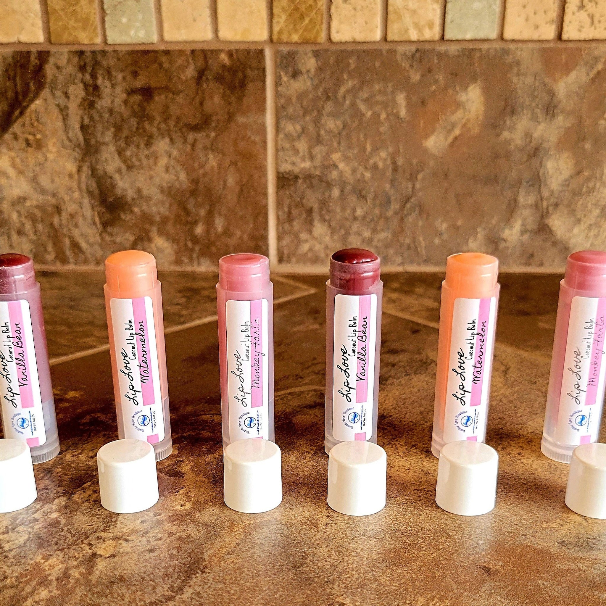 Tinted lip balm tubes with pink and white labels, Bubble Love Boutique brand, on a brown surface.