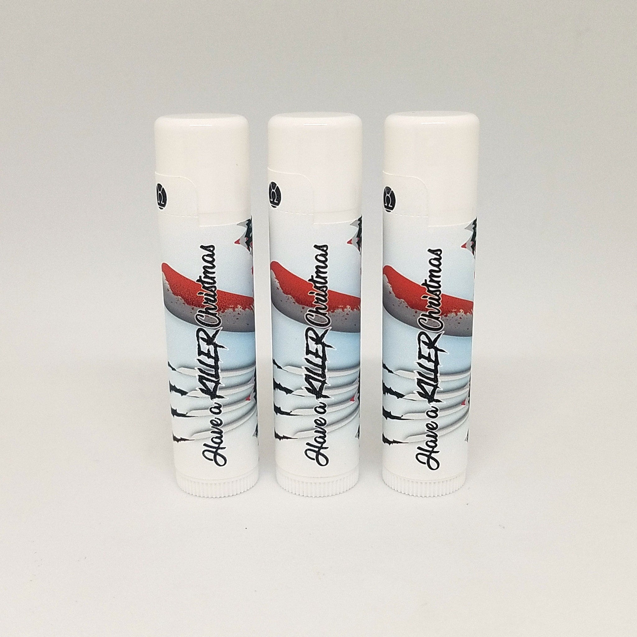 Lip balm tubes, white plastic with printed design including red and black text "Have a Killer Christmas