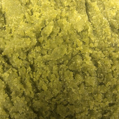 Green granular substance with a textured surface and small white specks