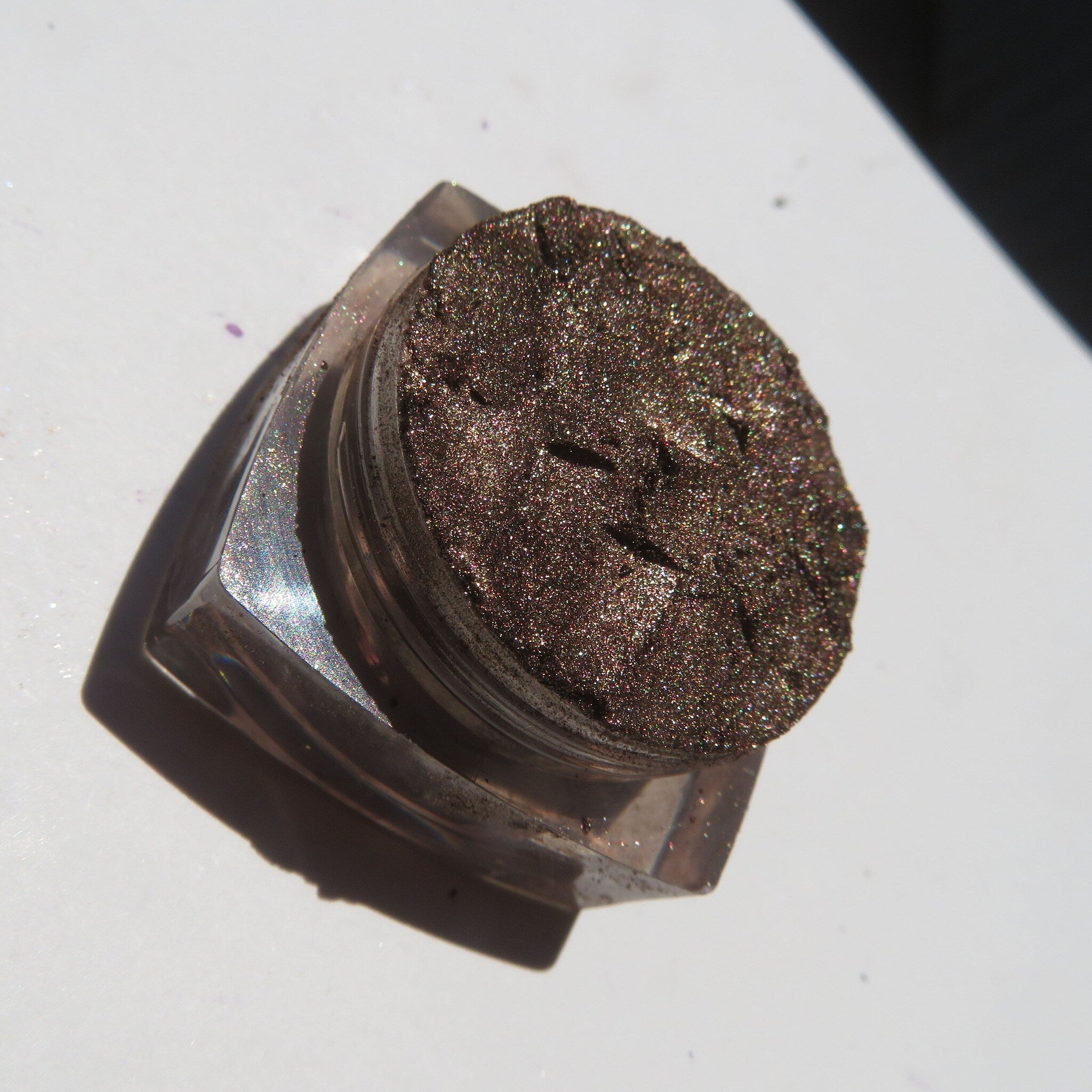 Open compact showing loose chocolate brown gold shimmer eyeshadow with eco-friendly packaging and brush applicator