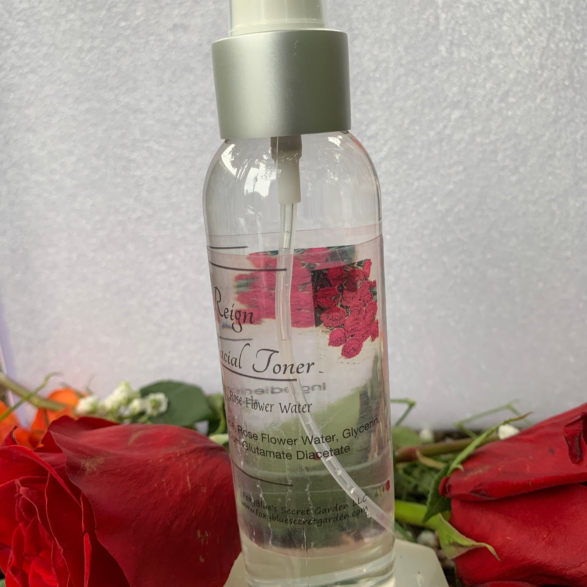 Facial toner bottle with clear glass, silver cap, and floral label, with Reign text visible