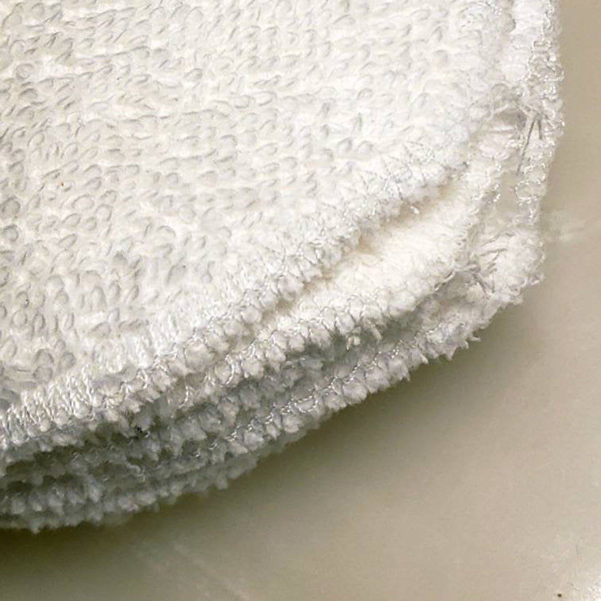 White terrycloth rounds with textured pattern and stitched edge detail