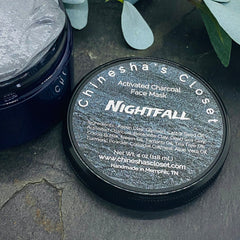 Activated charcoal face mask in dark blue jar, gray mask inside, and brand name on lid