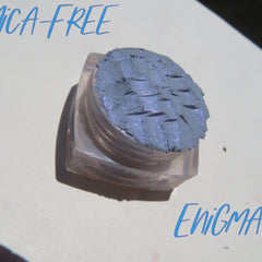Close-up of Enigma Blue Shimmer loose mineral eyeshadow with reflective particles in glass jar