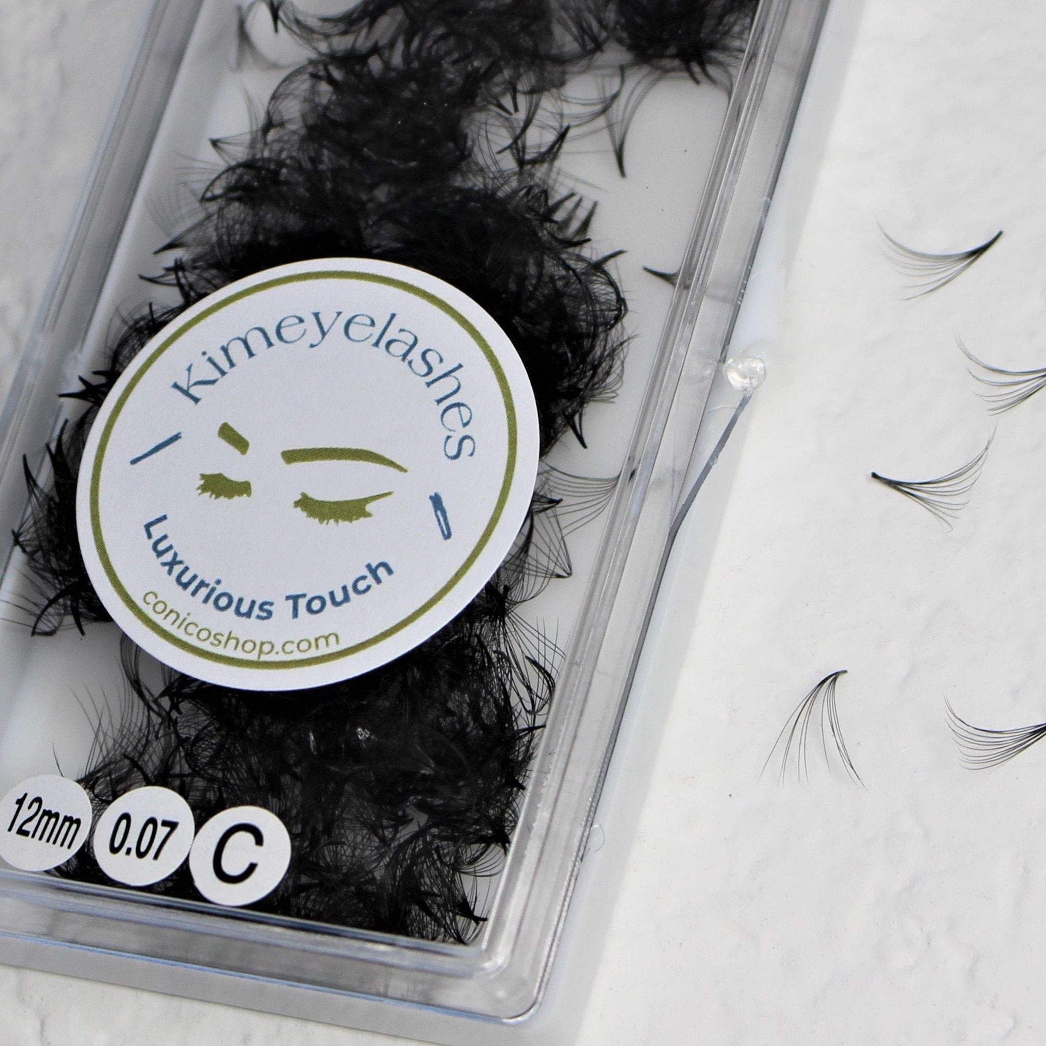 Eyelash extensions in black, synthetic material, Kimeyelashes brand, in clear plastic packaging, individual lashes visible