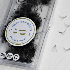 Eyelash extensions in black, synthetic material, Kimeyelashes brand, in clear plastic packaging, individual lashes visible