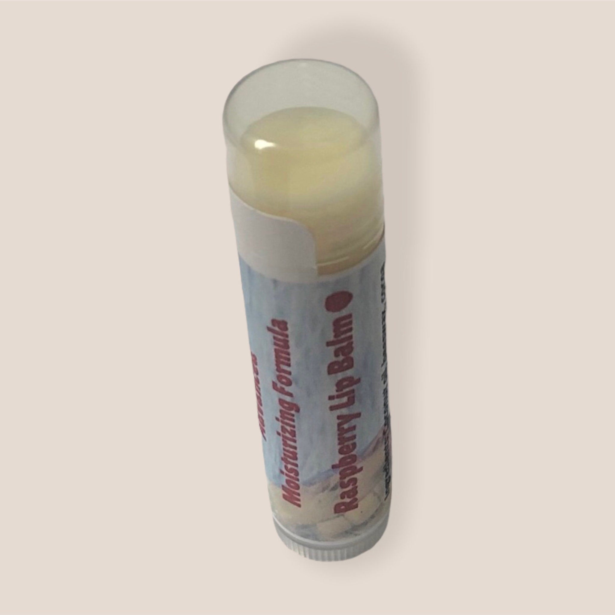 Raspberry lip balm with clear cap, white and blue label, Rock Island Naturals text visible