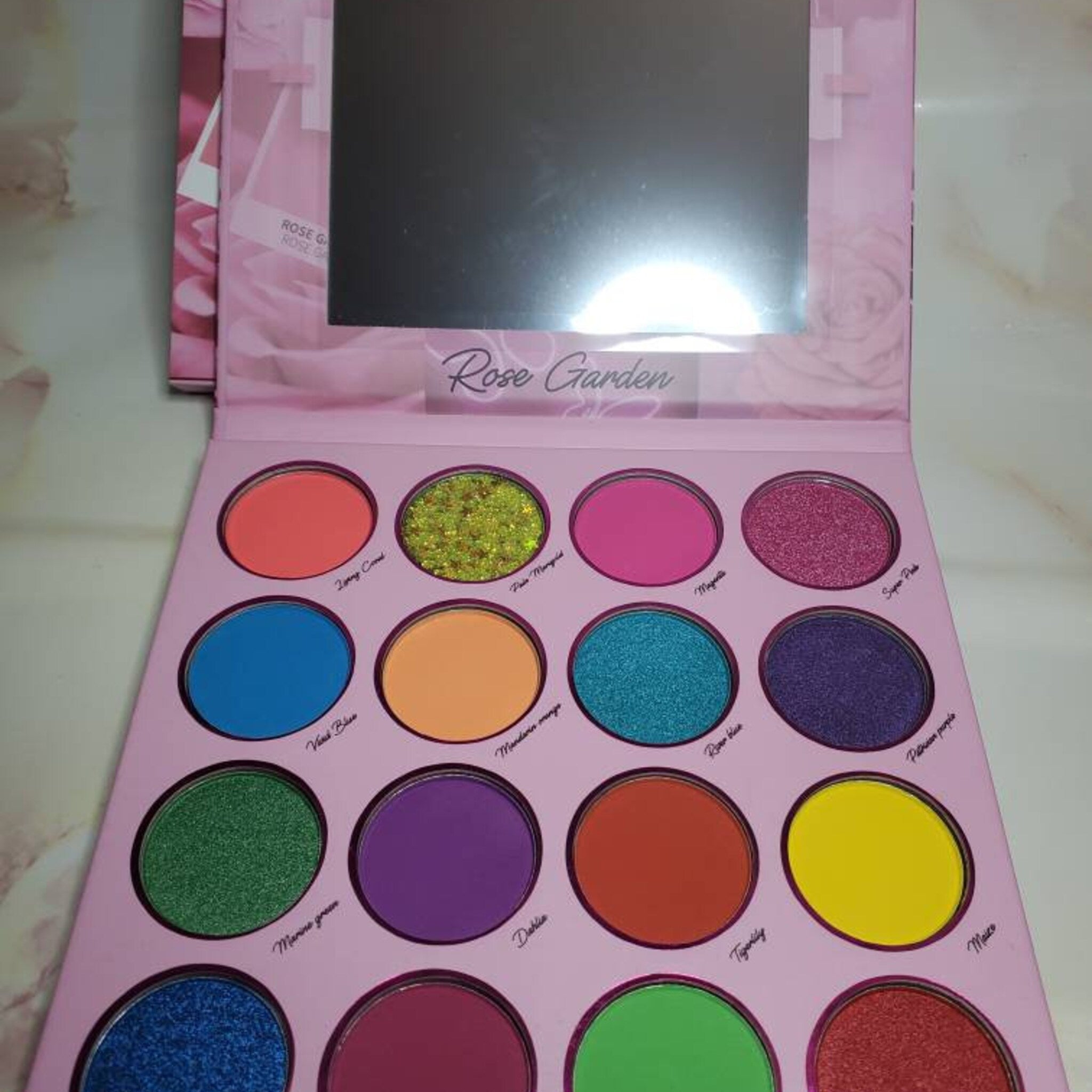 Side view of Sunflower Rose Garden eyeshadow palette showing gradient of warm pink and gold shades in rectangular pans