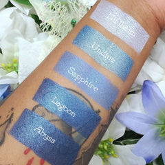 Close-up of sapphire blue vegan eyeshadow being applied to eyelid with brush