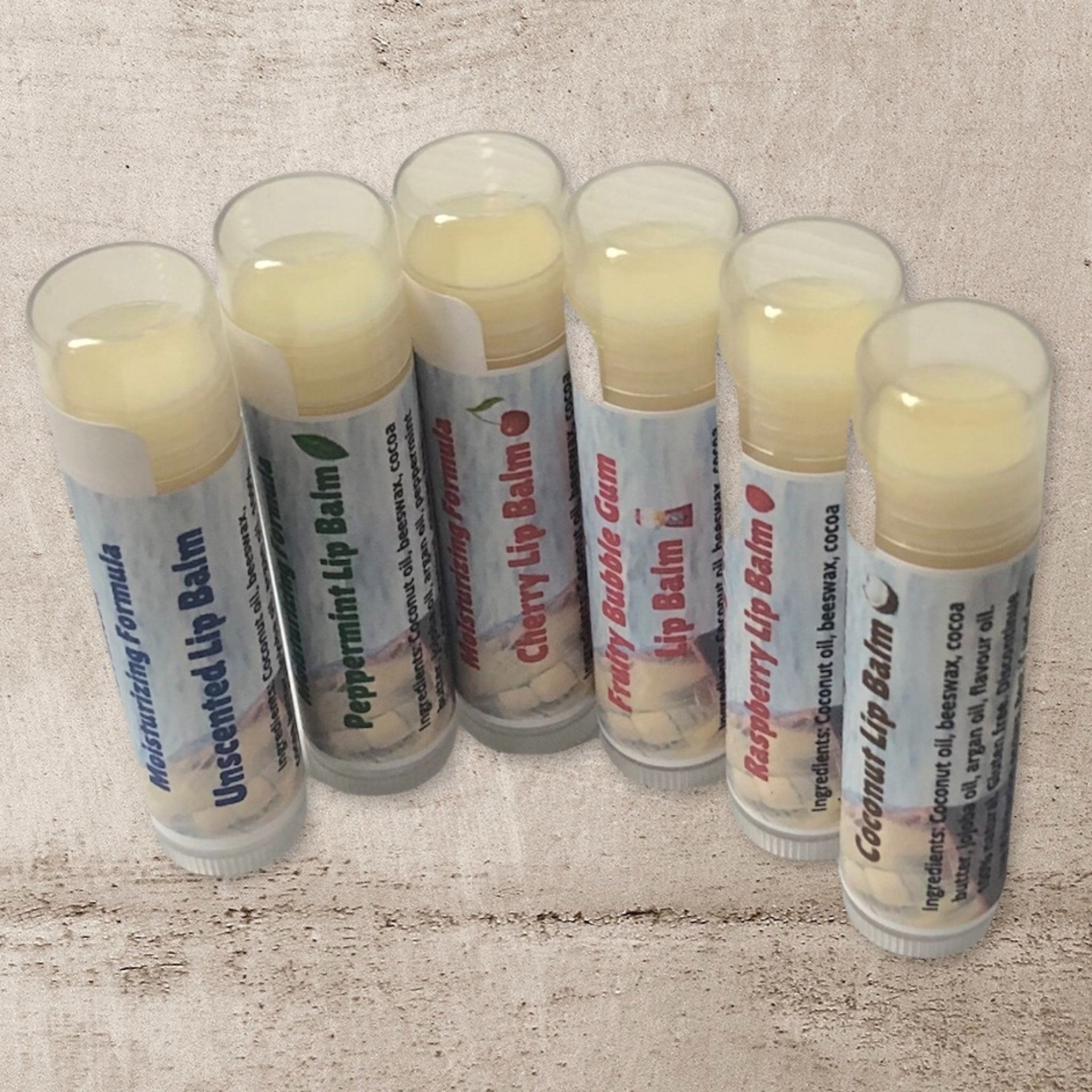 Lip balms in clear tubes with white labels, various flavors and Rock Island Naturals text visible