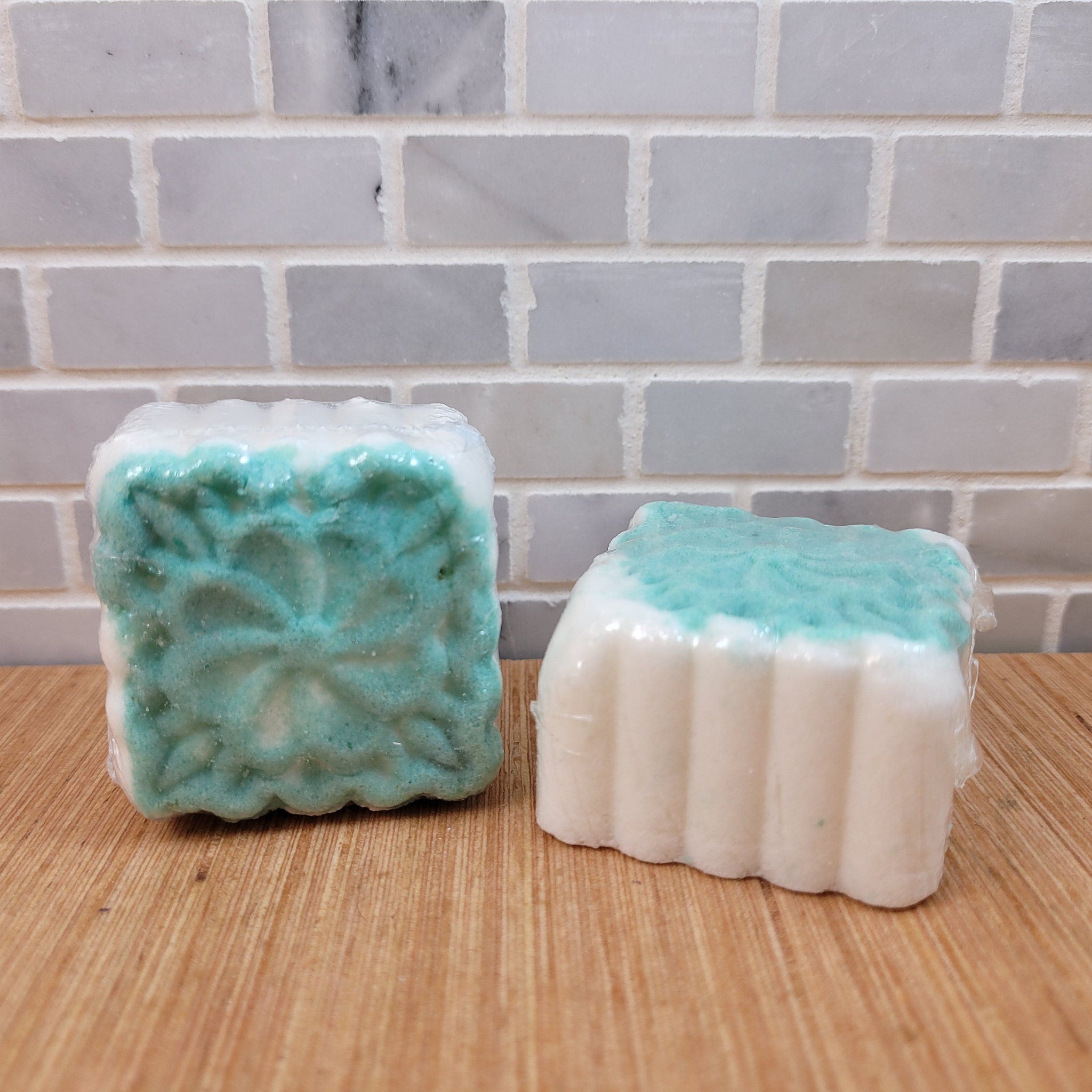 Bath bombs with green and white color, floral pattern, wrapped in plastic on wood surface