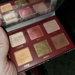 Close-up of shimmery taupe eye shadow palette with gradient shades and sleek black compact