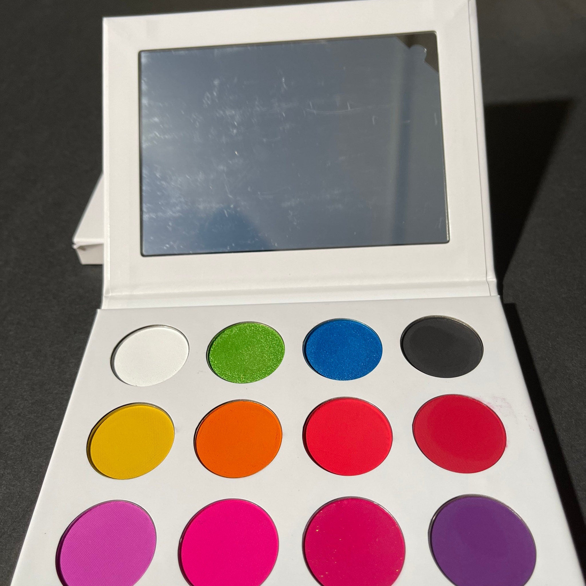 Close-up of Walter Tucci eyeshadow palette showing vibrant matte and shimmer shades in rich jewel tones