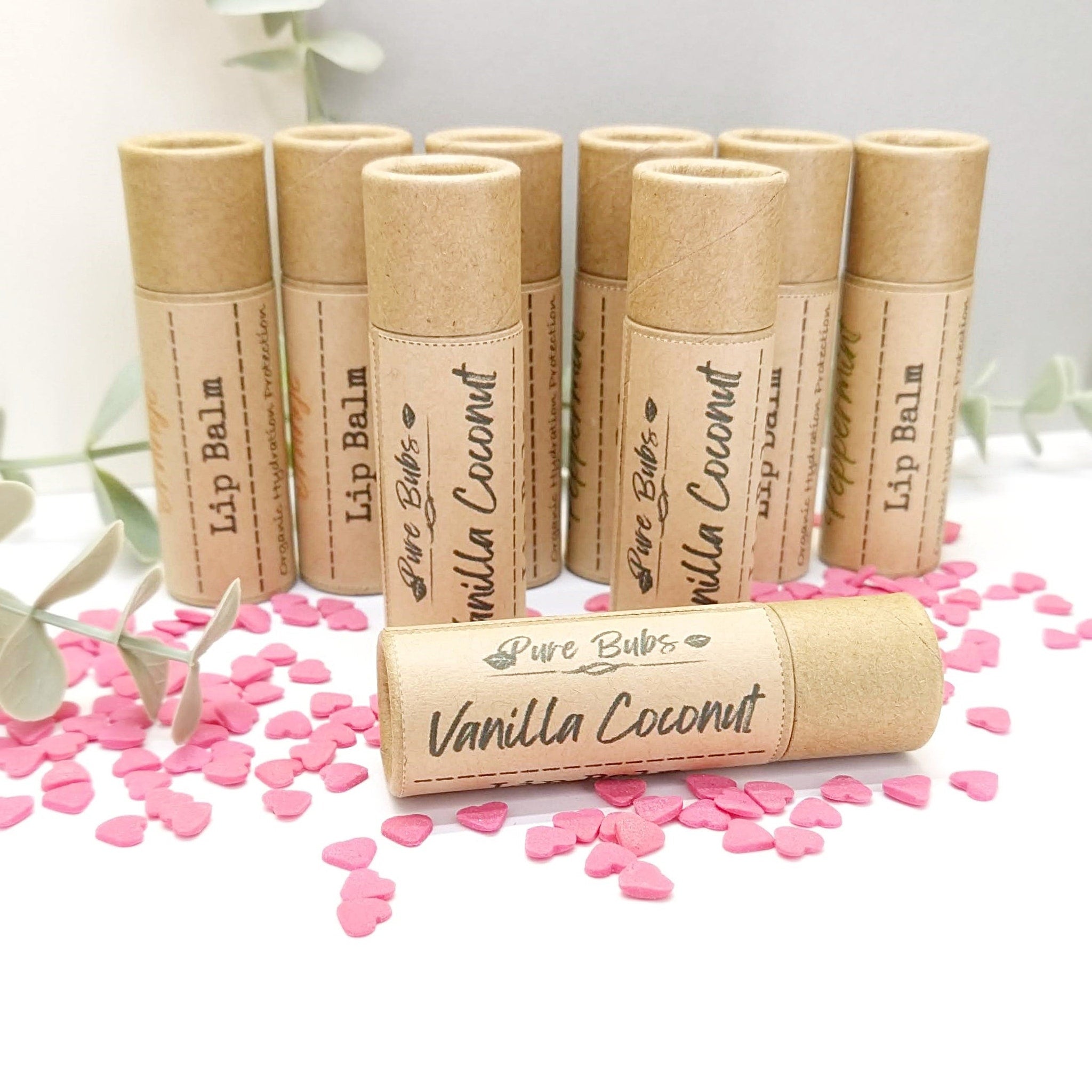 Lip balm tubes in beige cardboard with Vanilla Coconut label, Pure Bubs brand, and pink hearts around