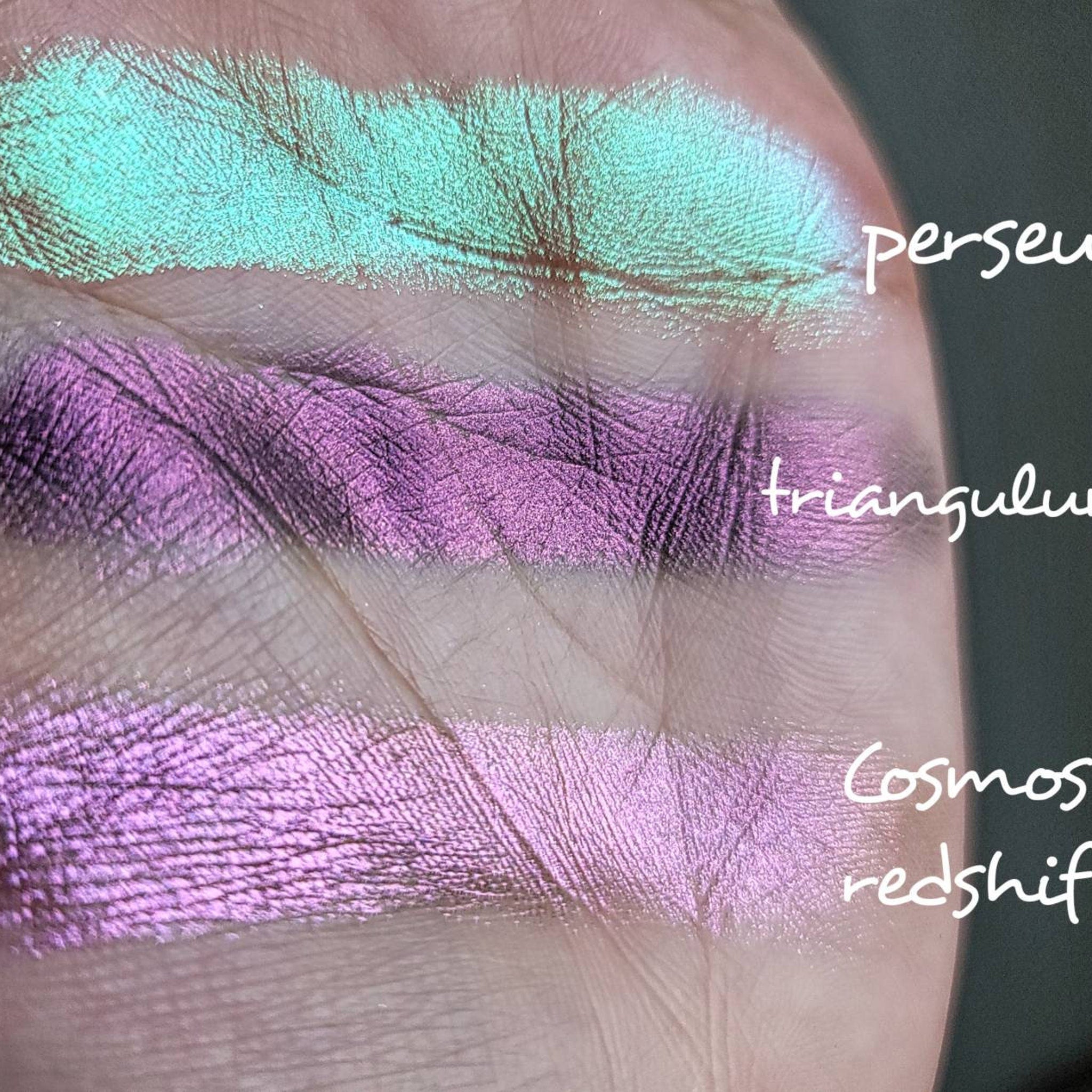 Close-up of vegan multichrome eyeshadow pan showing orange-to-violet shift with olive undertone on pressed powder surface