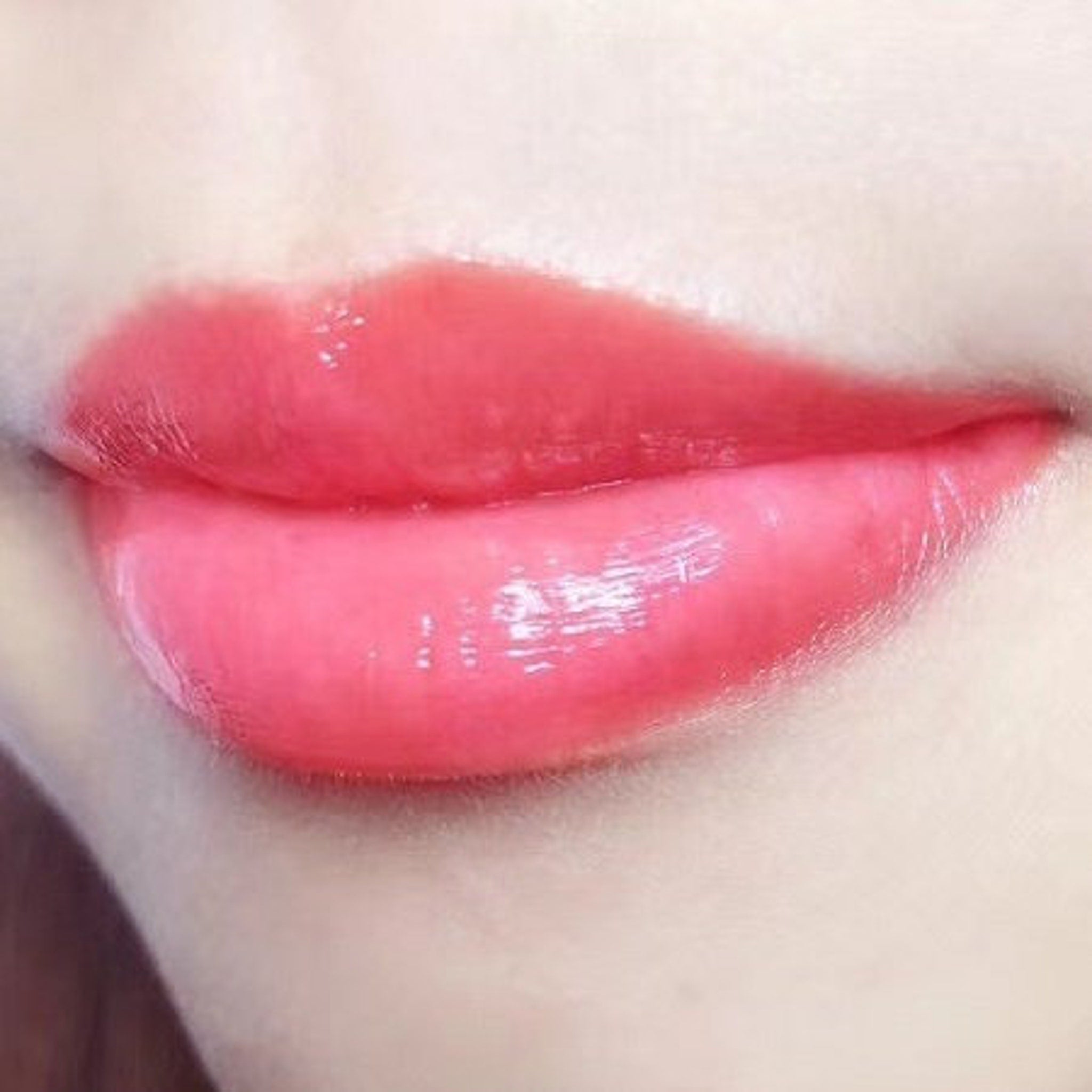 Lip gloss in glossy pink with wet appearance on lips and skin