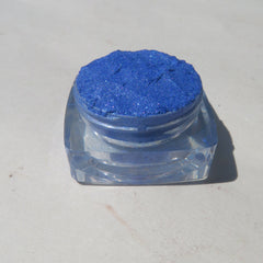 Close-up of vibrant blue shimmer loose mineral eyeshadow with reflective sparkle particles