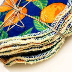Reusable cloth pads with orange fruit pattern, blue background, and natural twine tie