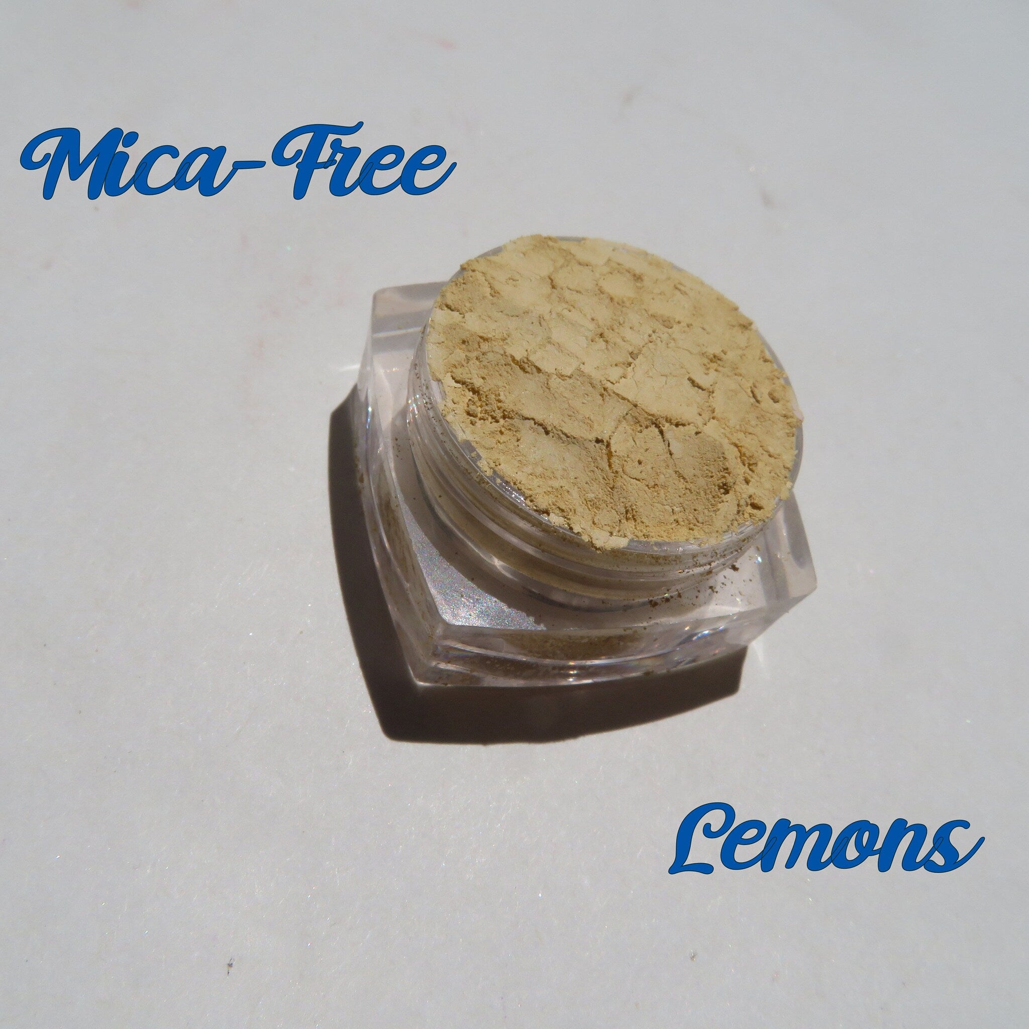 Bright yellow matte loose pigment eyeshadow in a clear jar with black screw-top lid, showcasing texture.