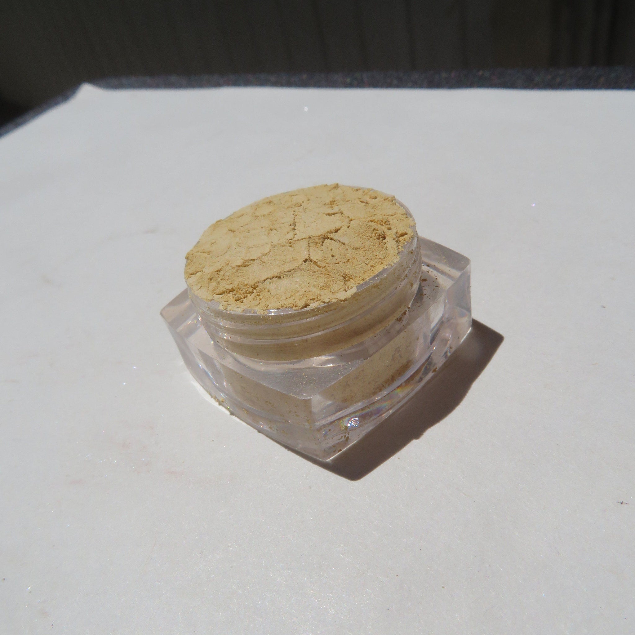 Close-up of bright yellow matte loose mineral eyeshadow with fine mica particles in a sifter jar
