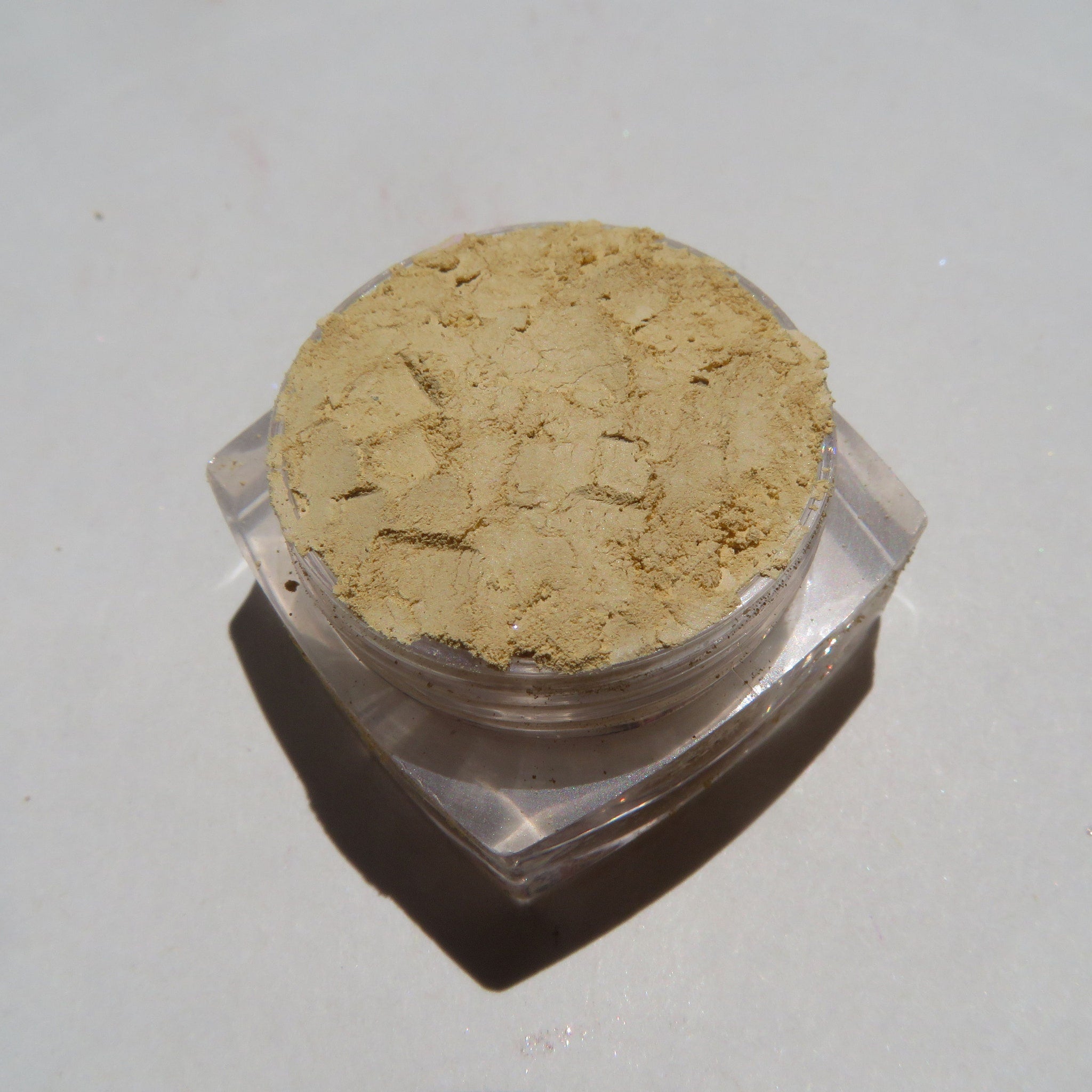 Side view of bright yellow matte mineral eyeshadow in loose pigment form with mica shimmer, showing texture detail