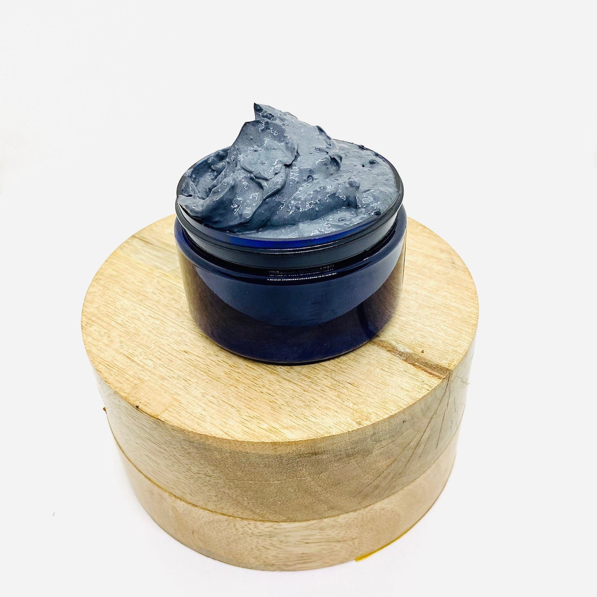 Face mask in a dark blue jar with gray mask material on a wooden block