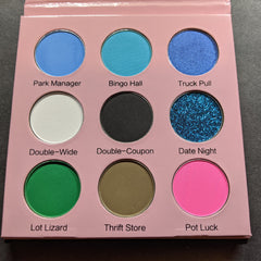 Eyeshadow palette with various colors, including blue, green, and pink, in a pink case