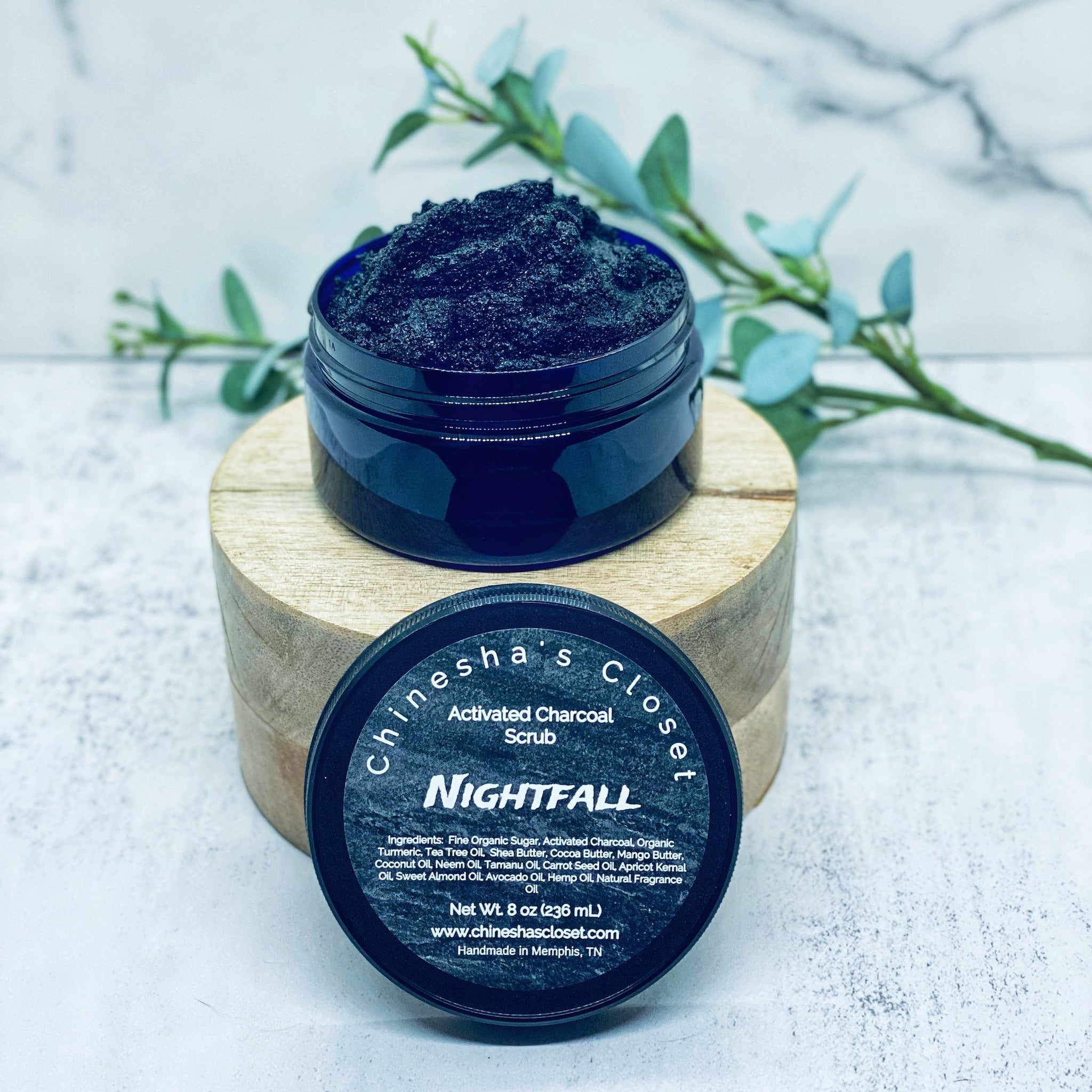 Activated charcoal scrub in a dark blue jar with black contents and text on lid, "Nightfall