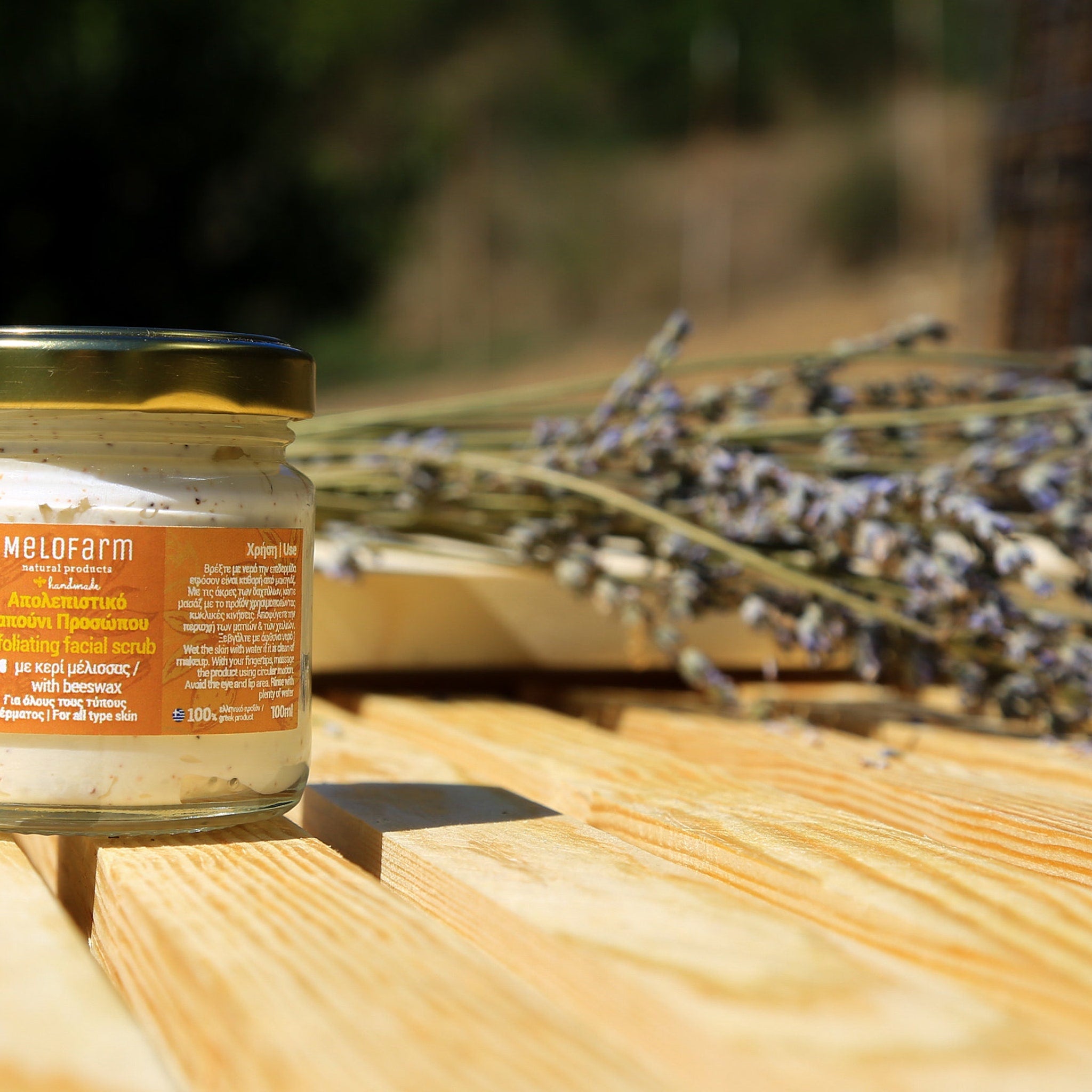 Facial scrub jar with gold lid, beige contents, and Melofarm label on wood surface