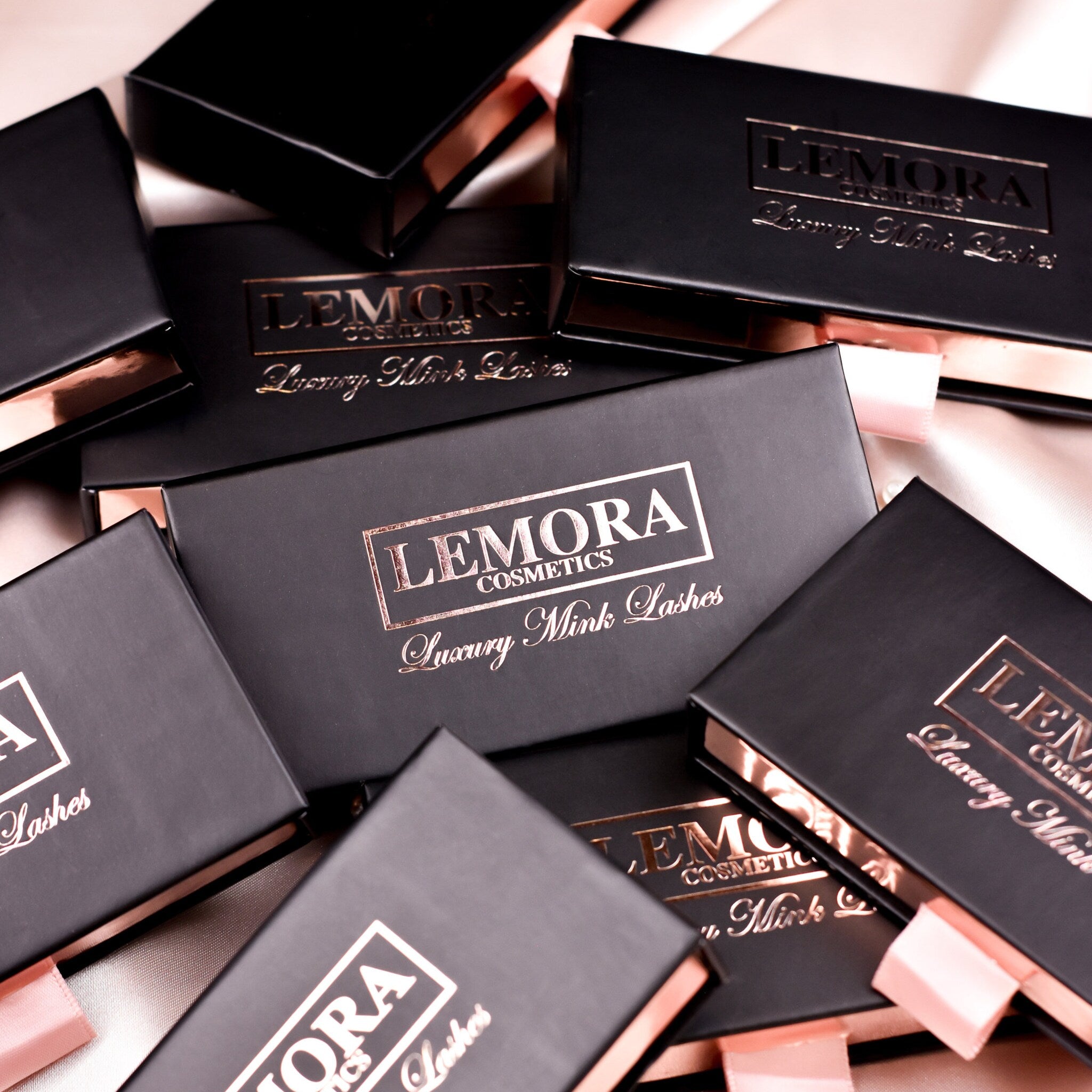Luxury Mink Lashes, black boxes with rose gold foil lettering, by LEMORA Cosmetics, on satin fabric