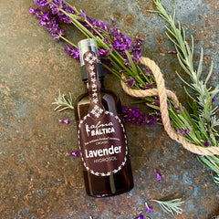 Lavender hydrosol bottle, brown glass, purple label with brand name, and lavender flowers on surface