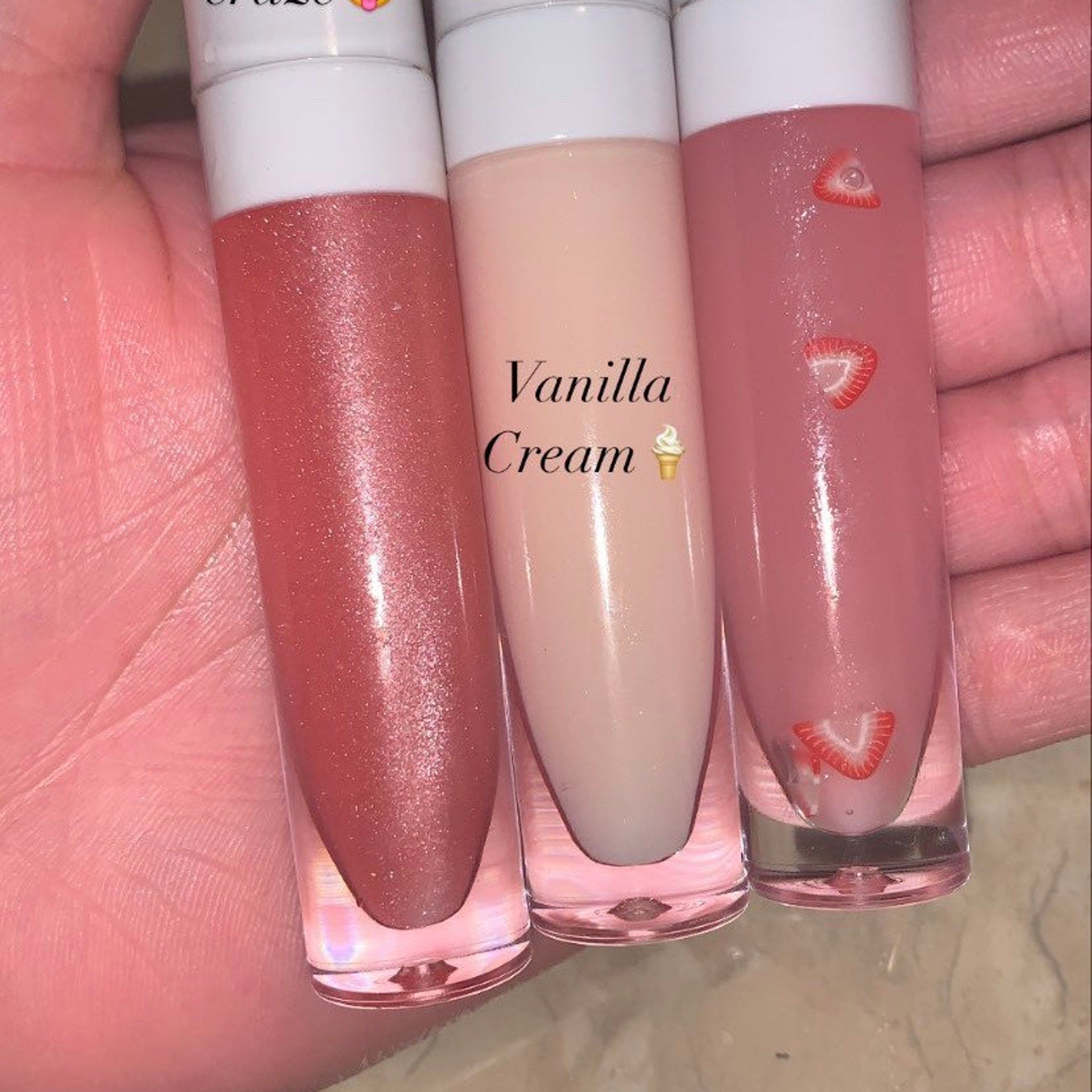 Lip gloss tubes with pink, peach, and clear liquid, strawberry slices, and text "Vanilla Cream