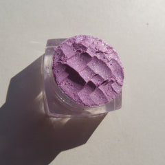 Purple eyeshadow with textured pattern in a clear container, close-up view