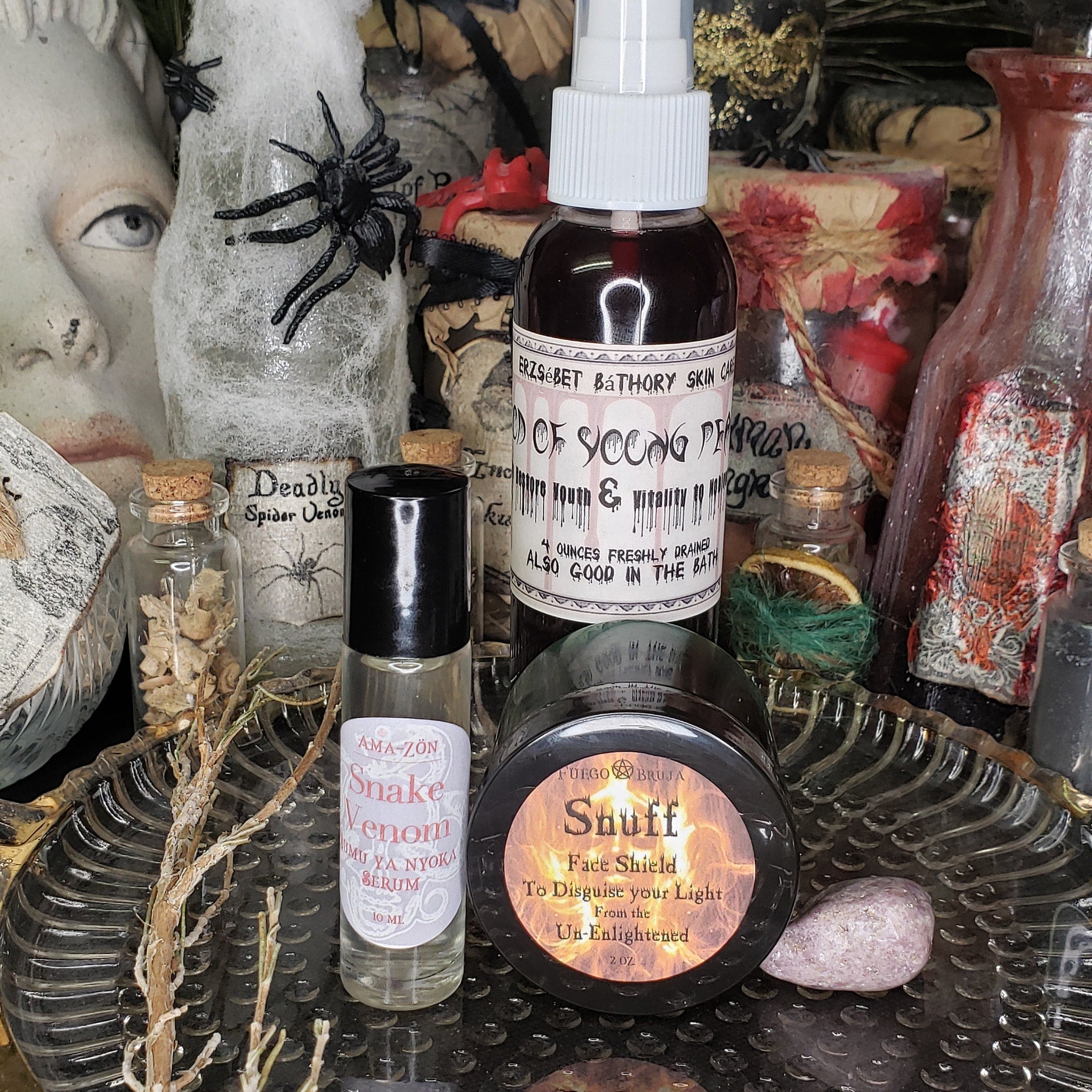 Bottles and jars with black, white, and clear containers, labels, and corks, with dried branches and a spider decoration