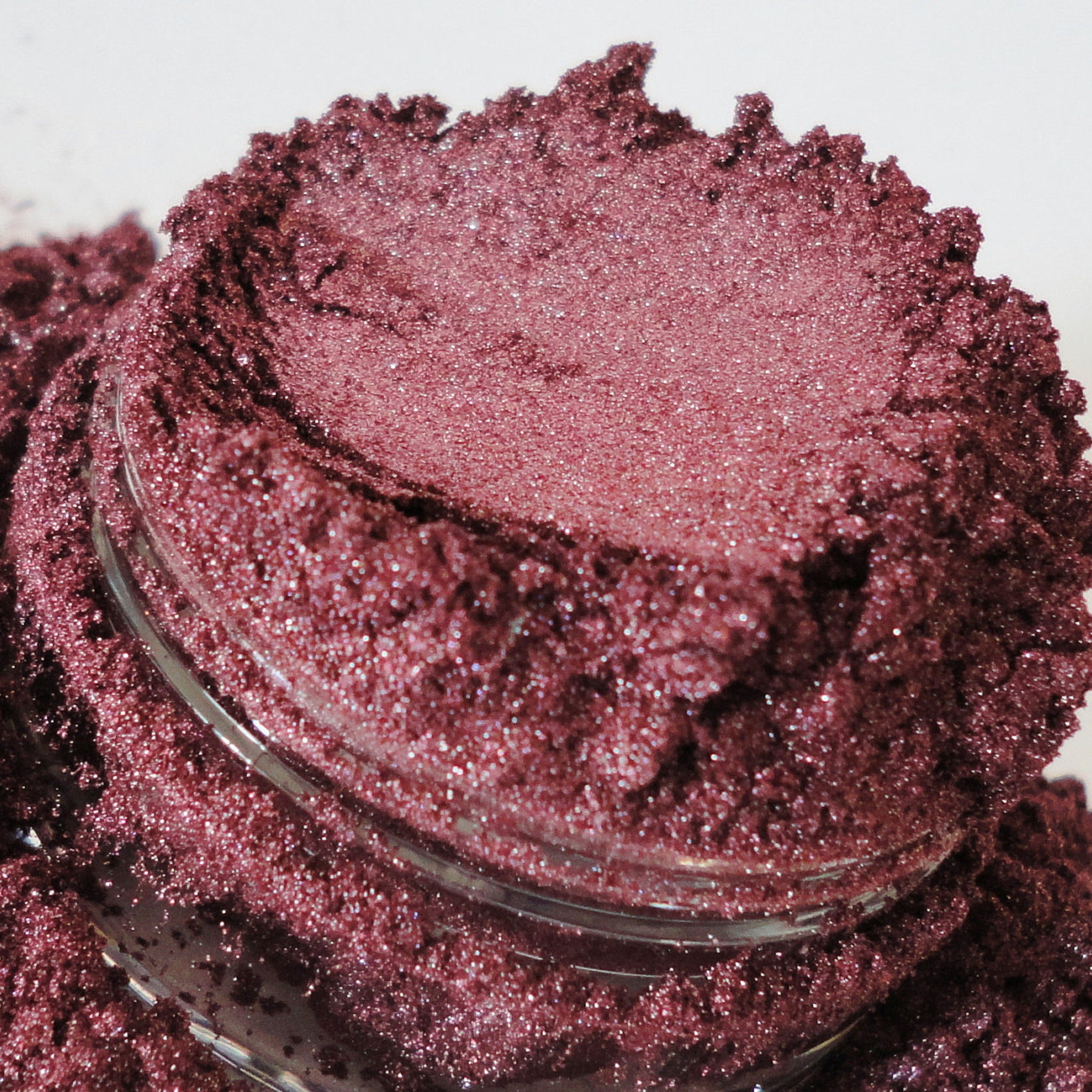 Red raspberry burgundy mineral eyeshadow in a black sifter jar with silver lid, showcasing rich pigmentation.