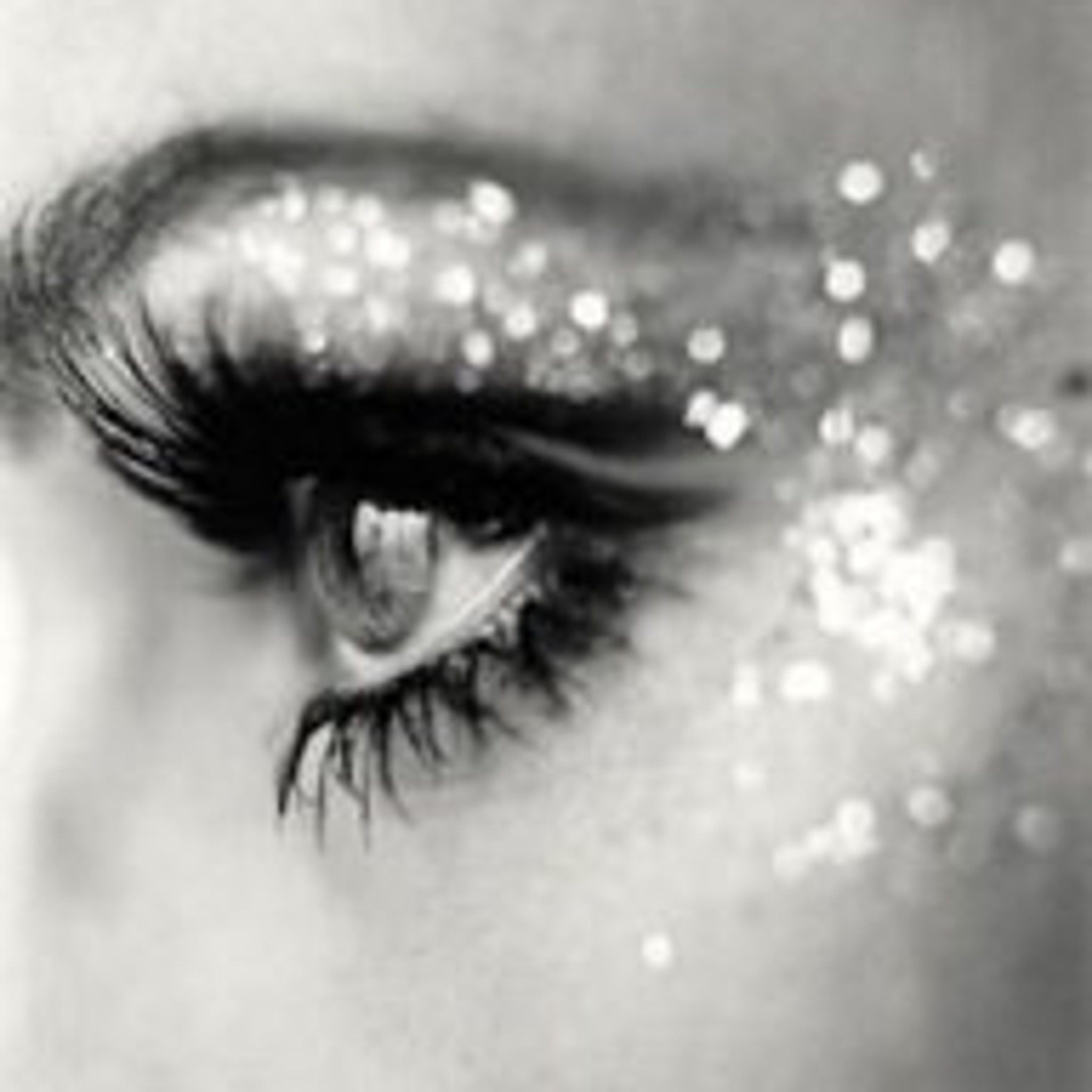 Silver glitter eyeshadow in a small round jar with black lid, displayed on a white background.