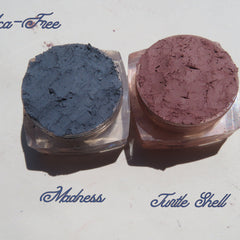 Side view of three matte loose mineral eyeshadows in glass jars showcasing earthy vegan pigments with sifter lids