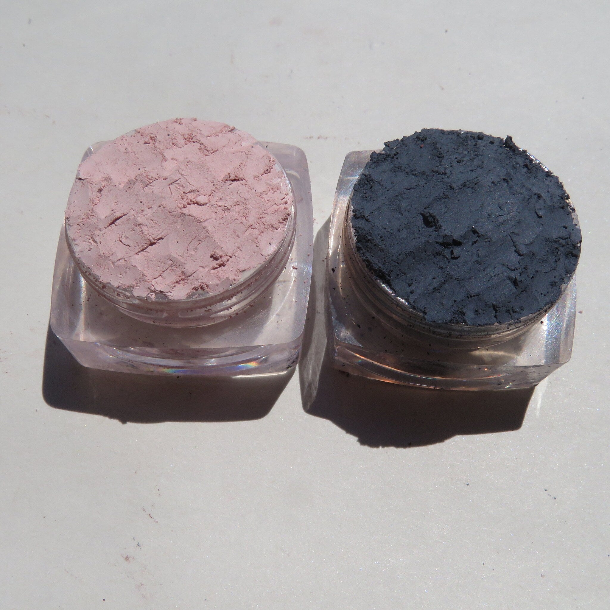 Close-up of three matte loose mineral eyeshadows in earthy tones with vegan labeling on sleek black jars