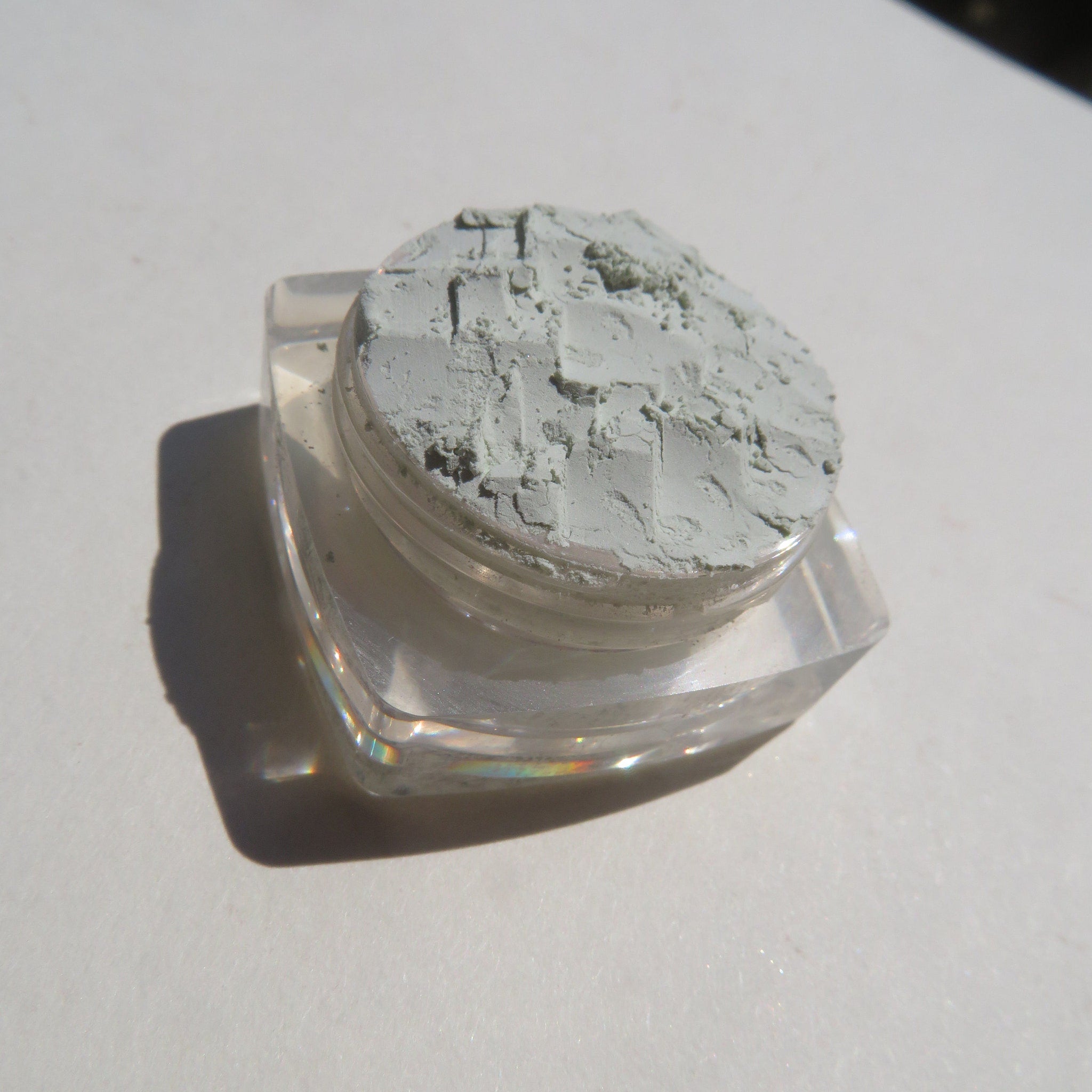 Hand applying matte pale green loose mineral eyeshadow with a fluffy brush for soft, blendable coverage