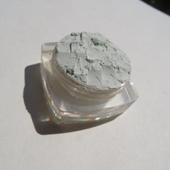 Hand applying matte pale green loose mineral eyeshadow with a fluffy brush for soft, blendable coverage