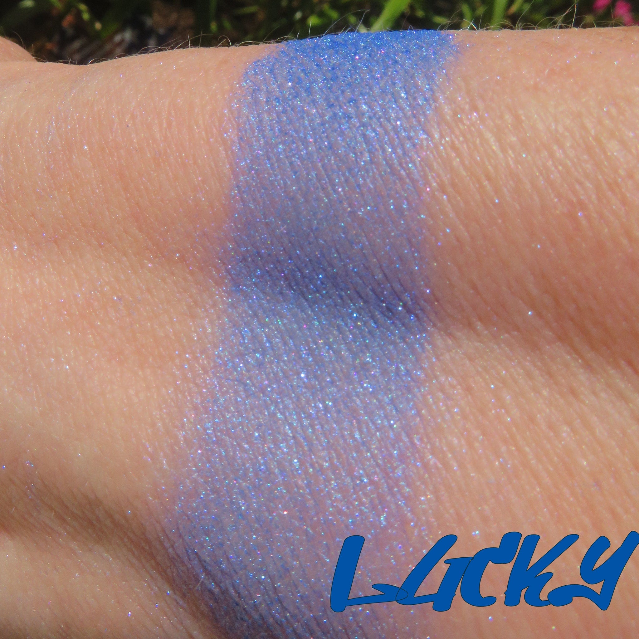 Side view of bright blue shimmer mineral eyeshadow in open jar showing loose pigment texture