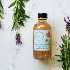 Toner bottle with black cap, clear glass, and Ballerina Botanicals label with lavender and green sprigs