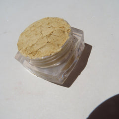 Close-up of vibrant bright yellow matte loose mineral eyeshadow with fine mica shimmer in a small jar.