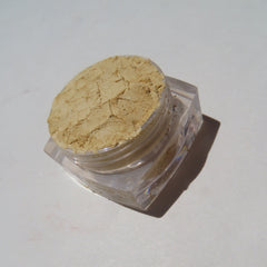 Hand applying bright yellow matte mineral eyeshadow with a fluffy brush onto eyelid.